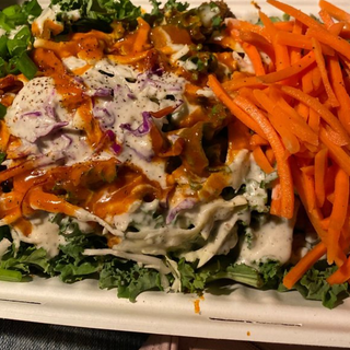 BUFFALO BOWL - Sriracha lime buffalo chik'n, dill peppercorn ranch, cilantro, kale super food salad, sriracha lime buffalo sauce, carrots and scallions on a bed of jasmine rice.